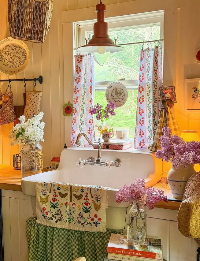Farmhouse Kitchen Design Ideas: 36 Ways to Get the Look 19 Farmhouse kitchen decor with a vintage drainboard sink, green gingham skirt, cherry-print curtains, and fresh lilacs