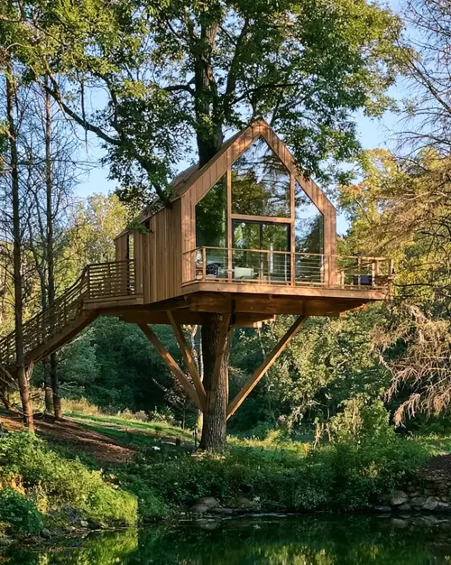 55 Treehouse Design Ideas, From Backyard Platforms to Canopy Cabins 20 Simple treehouse design ideas with a glazed timber gable cabin on a braced post above a pond