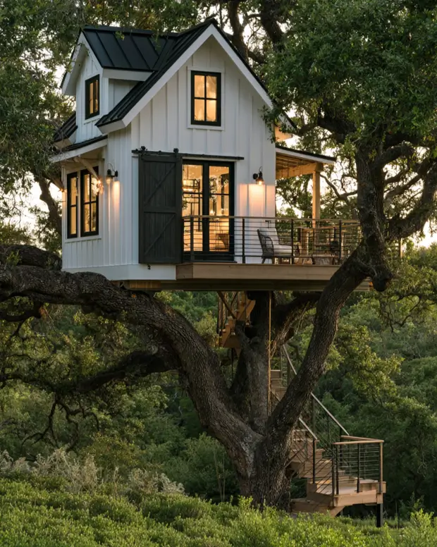 55 Treehouse Design Ideas, From Backyard Platforms to Canopy Cabins 22 Treehouse design ideas with white board and batten cladding, a black sliding barn door and a turning stair up an oak