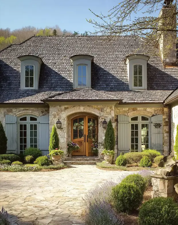 French Country House Style: An Architect's Guide to the Exterior Look 28 French Country House Design home with eyebrow dormers, a deep cedar-shingle roof, and arched stone entry