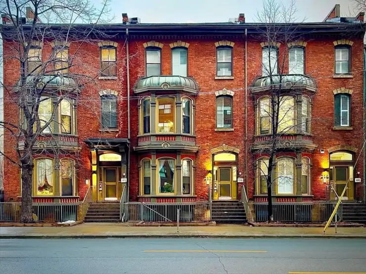 Italianate Style House: 33 Ideas and the Details That Give One Away 29 Row of red brick Italianate style houses sharing one bracketed cornice with copper-hooded bay windows