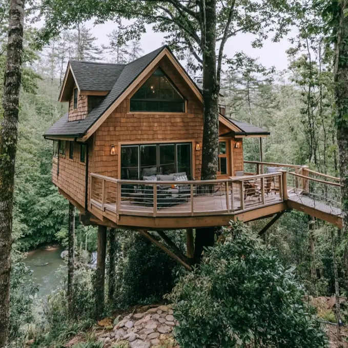 55 Treehouse Design Ideas, From Backyard Platforms to Canopy Cabins 40 Treehouse design ideas with cedar shingle cladding and a wraparound corner deck on braced posts above a river