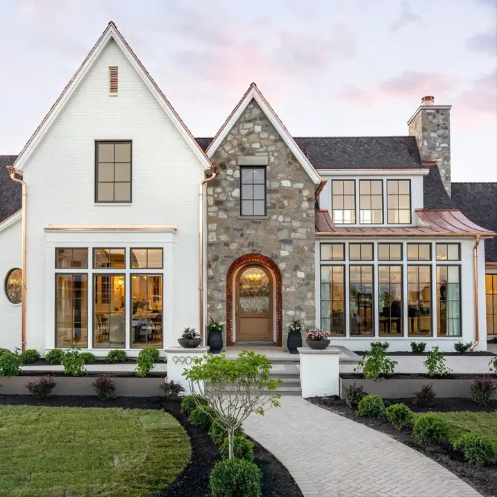 White Farmhouse with Stone Exterior: 29 Ideas That Feel Warm, Not Cold 6 Modern farmhouse with stone exterior entry gable, arched wood door, and copper gutters against white painted brick