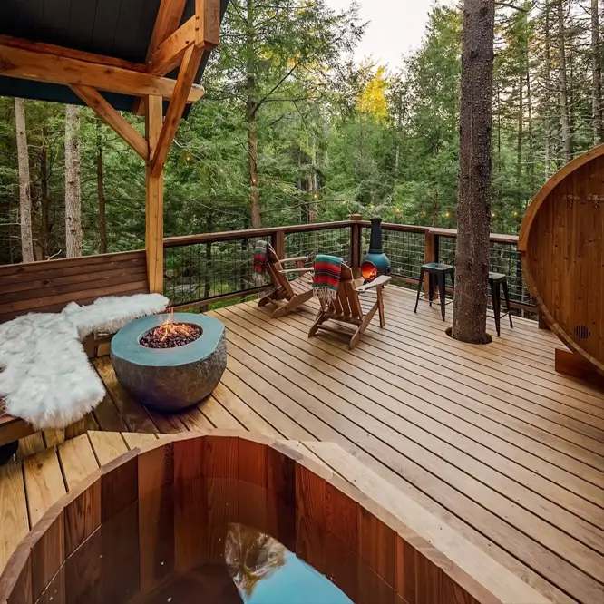 55 Treehouse Design Ideas, From Backyard Platforms to Canopy Cabins 51 Treehouse design ideas showing a timber deck with a fire bowl, cedar hot tub and a spruce trunk passing through an opening