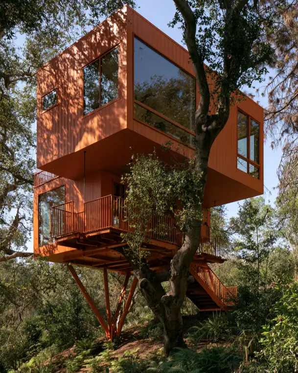 55 Treehouse Design Ideas, From Backyard Platforms to Canopy Cabins 7 Modern treehouse design ideas with stacked terracotta-clad volumes on splayed steel legs beside a mature oak