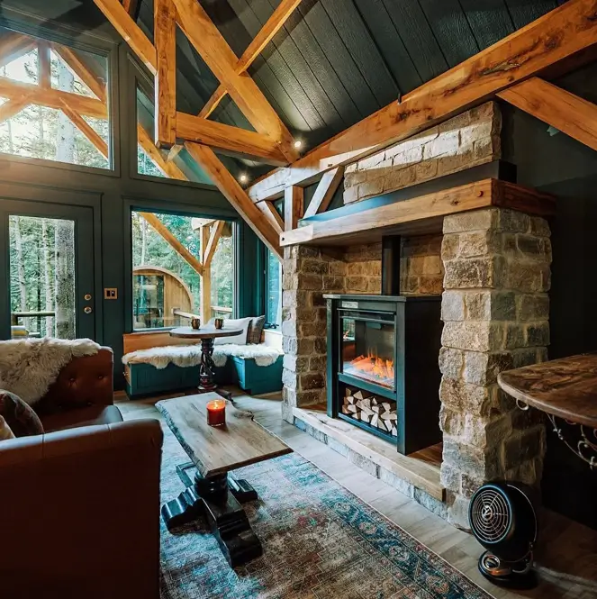 55 Treehouse Design Ideas, From Backyard Platforms to Canopy Cabins 53 Treehouse design ideas interior with a stacked stone fireplace chimney, timber mantel and window seats under forest glazing