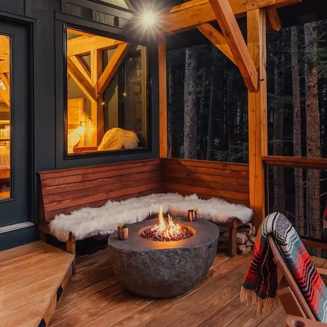 55 Treehouse Design Ideas, From Backyard Platforms to Canopy Cabins 57 Treehouse design ideas with a built-in corner bench, stone fire bowl and timber post frame on a forest deck