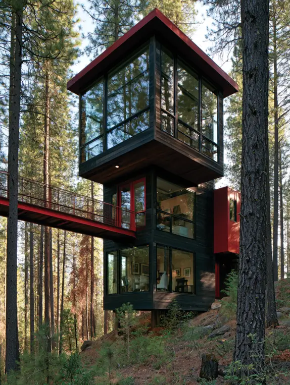 55 Treehouse Design Ideas, From Backyard Platforms to Canopy Cabins 10 Modern treehouse design ideas with a charred black timber tower, red roof edge and a red steel bridge entry