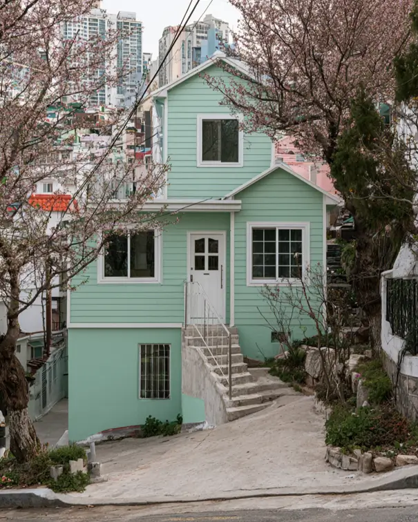 43 Green House With White Trim Ideas for Fresh Curb Appeal 13 mint green house with white trim, white front door, and cherry blossoms on a hillside cottage