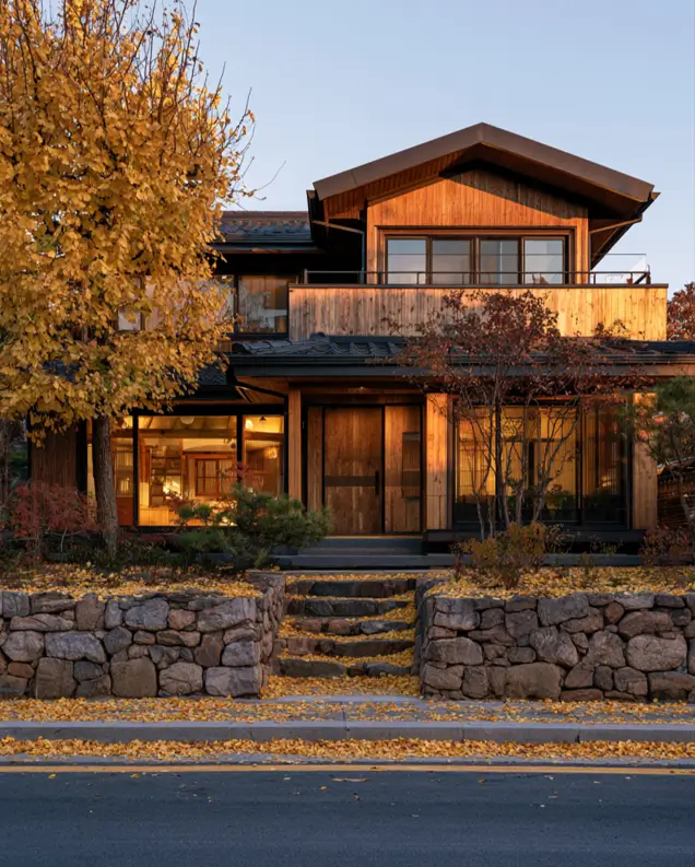 37 Brown House with Black Trim Ideas for a Warm, Modern Exterior 16 Warm brown wood Japanese-style home with dark tiled roofs, charcoal window frames, and a black balcony rail among ginkgo