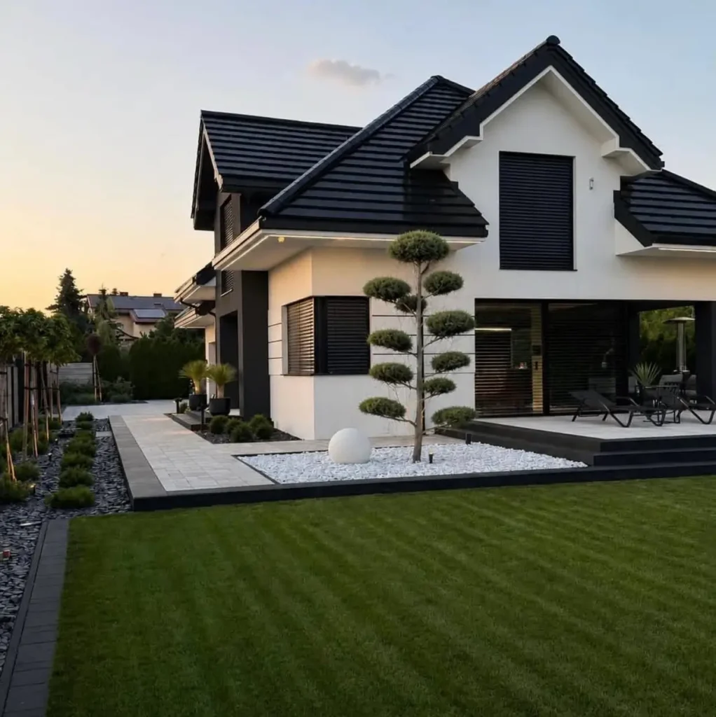 46 Modern Black and White House Exterior Ideas for a Timeless Look 4 White stucco home with a black tiled roof and black shutters at dusk