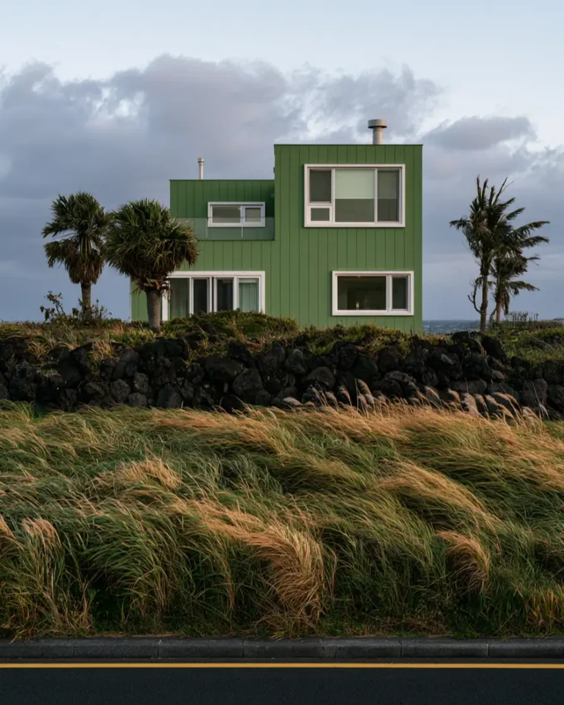 43 Green House With White Trim Ideas for Fresh Curb Appeal 22 mid green house with white trim and white window frames on a modern flat-roofed coastal home above a stone wall