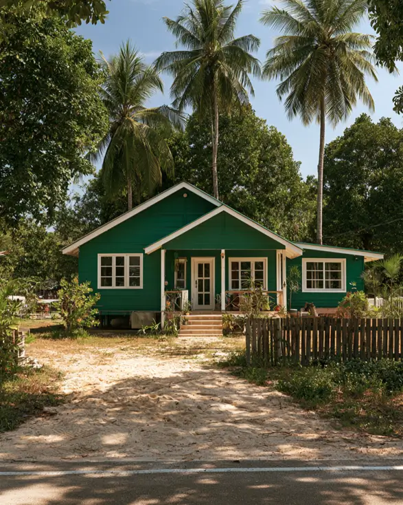 43 Green House With White Trim Ideas for Fresh Curb Appeal 27 emerald green house with white trim, white French doors, and gable trim on a tropical island cottage under palm trees