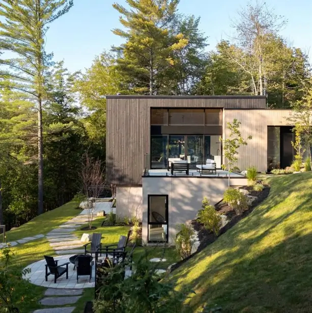 Hillside House Design: 38 Ideas for Building With the Slope 5 Nordic cabin with wood siding and a stucco base built into a grassy hillside slope