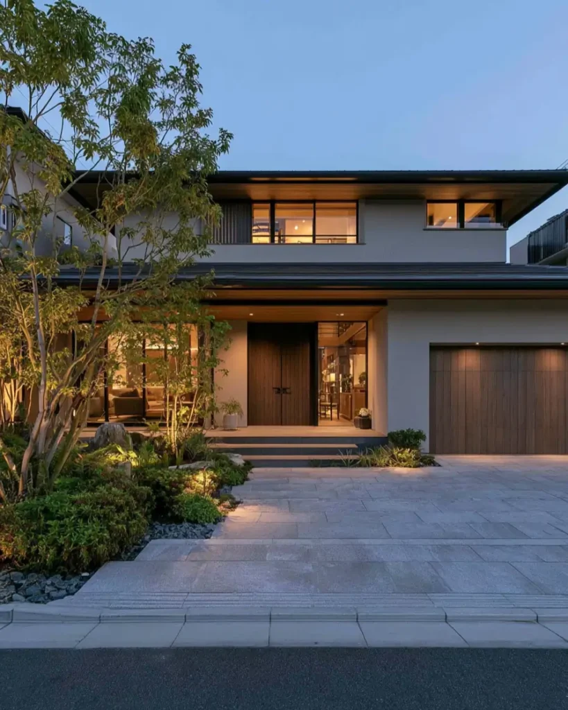 Modern Japanese House Design: 58 Ideas, Costs, and What Defines the Style 41 An uplit entry garden with stone paving below deep eaves lined in warm timber at dusk.