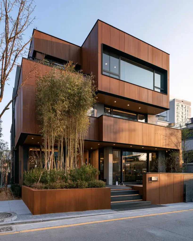 37 Brown House with Black Trim Ideas for a Warm, Modern Exterior 6 Rust-brown Corten steel mansion with stacked volumes, black-framed ribbon windows, and bamboo at the entry