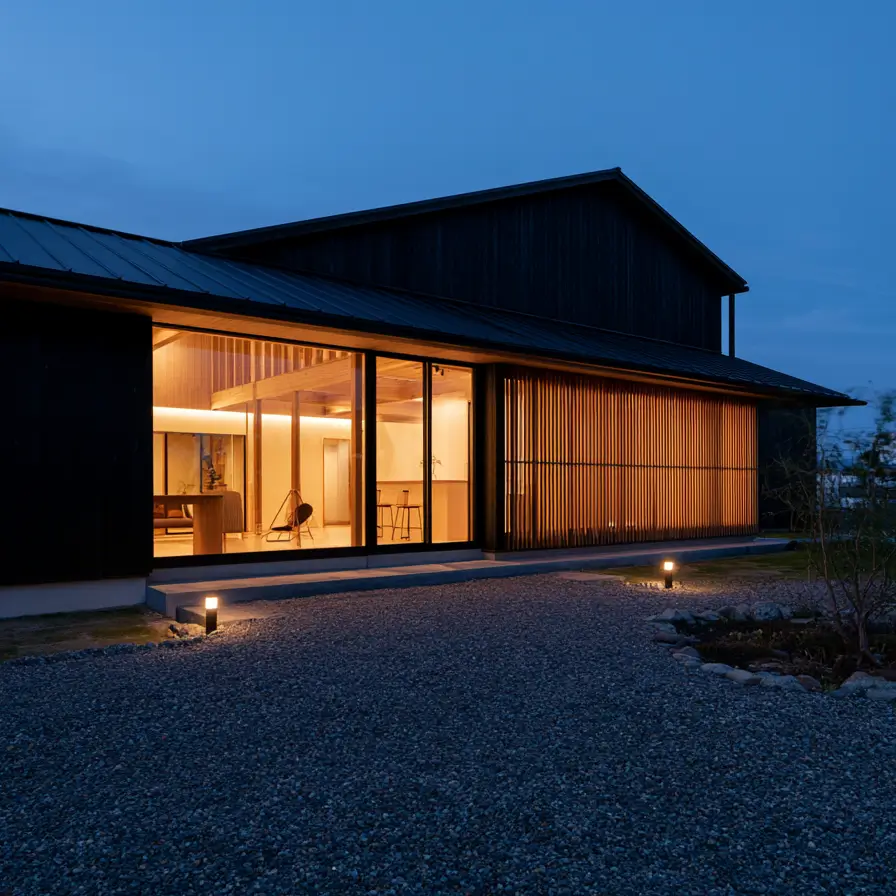 Modern Japanese House Design: 58 Ideas, Costs, and What Defines the Style 42 Warm light along a long glazed band between a dark gabled volume and a timber screen at dusk.