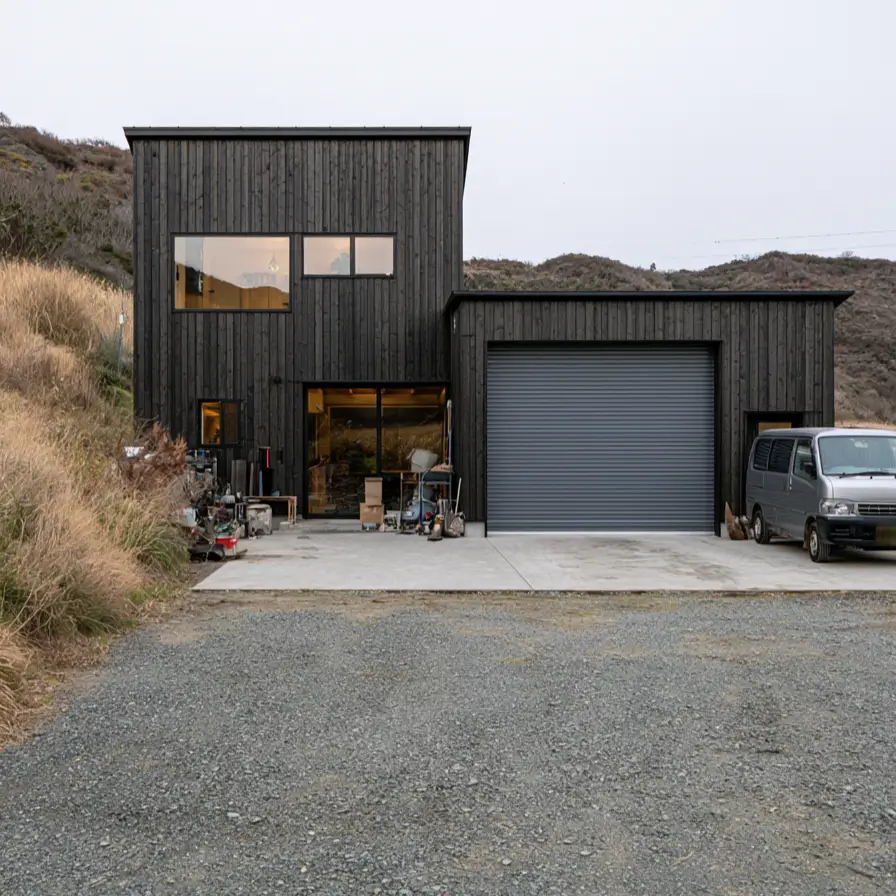 Modern Japanese House Design: 58 Ideas, Costs, and What Defines the Style 44 Charred timber cladding across a house joined to a workshop bay with a wide roller shutter.