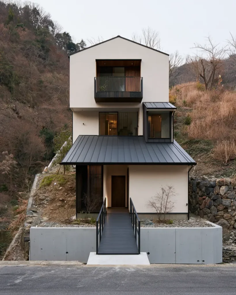Modern Japanese House Design: 58 Ideas, Costs, and What Defines the Style 47 A narrow steel bridge crossing to the door of a hillside house behind a poured concrete wall.