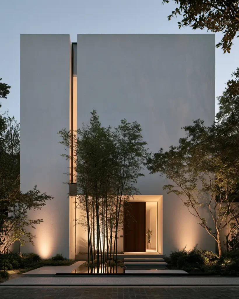 Modern Japanese House Design: 58 Ideas, Costs, and What Defines the Style 7 A narrow lit glass slot dividing two render volumes at dusk, with bamboo and a water strip below.