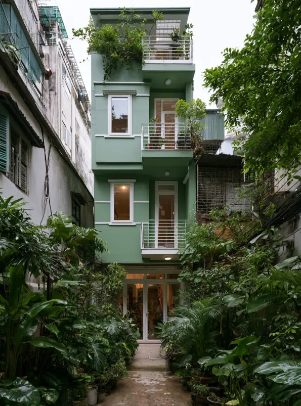 43 Green House With White Trim Ideas for Fresh Curb Appeal 8 sage green house with white trim, planted balconies, and white railings on a narrow urban tube house