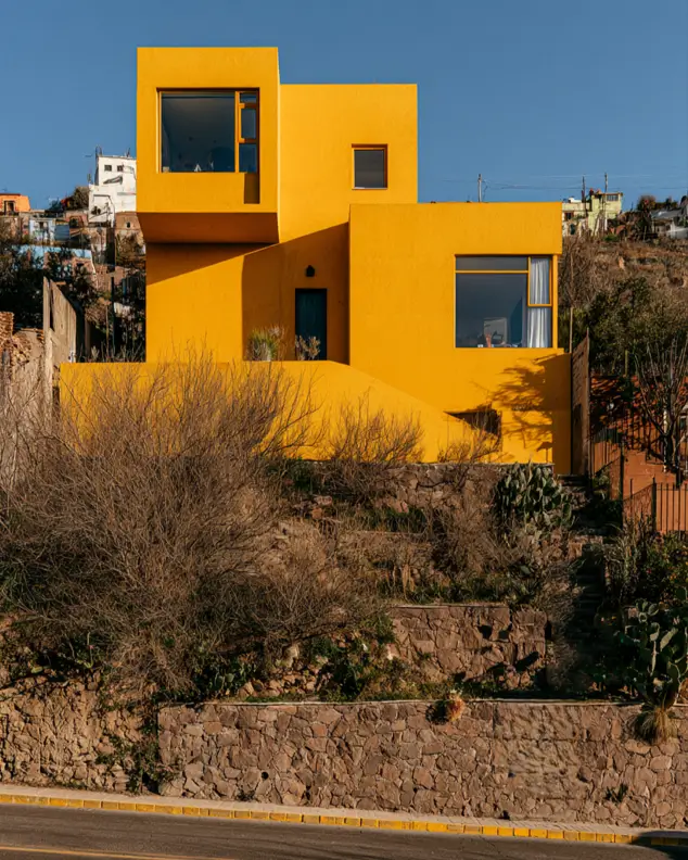 Hillside House Design: 38 Ideas for Building With the Slope 11 bold yellow stucco hillside house design in stacked cubes above stone retaining walls on a terraced slope