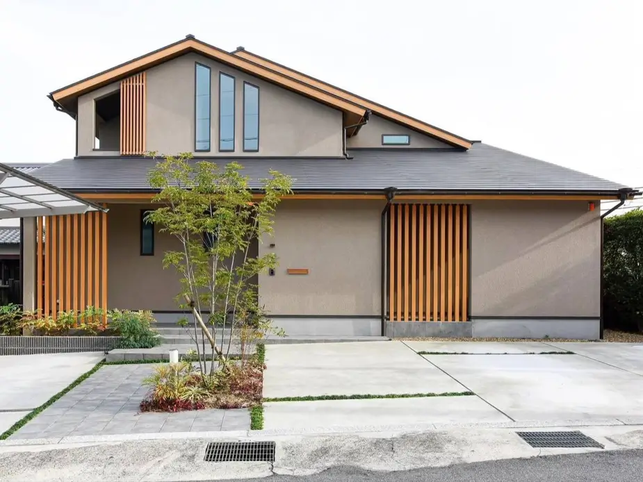 Modern Japanese House Design: 58 Ideas, Costs, and What Defines the Style 2 A modern Japanese house with a sweeping dark tiled roof, taupe render walls, and vertical cedar screens.