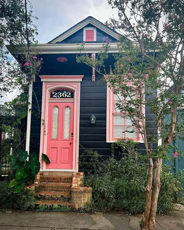 26 Black and Pink Houses Worth Saving Before You Paint 3 Black and pink house exterior on a Creole shotgun cottage, with a coral-pink door and trim against black siding